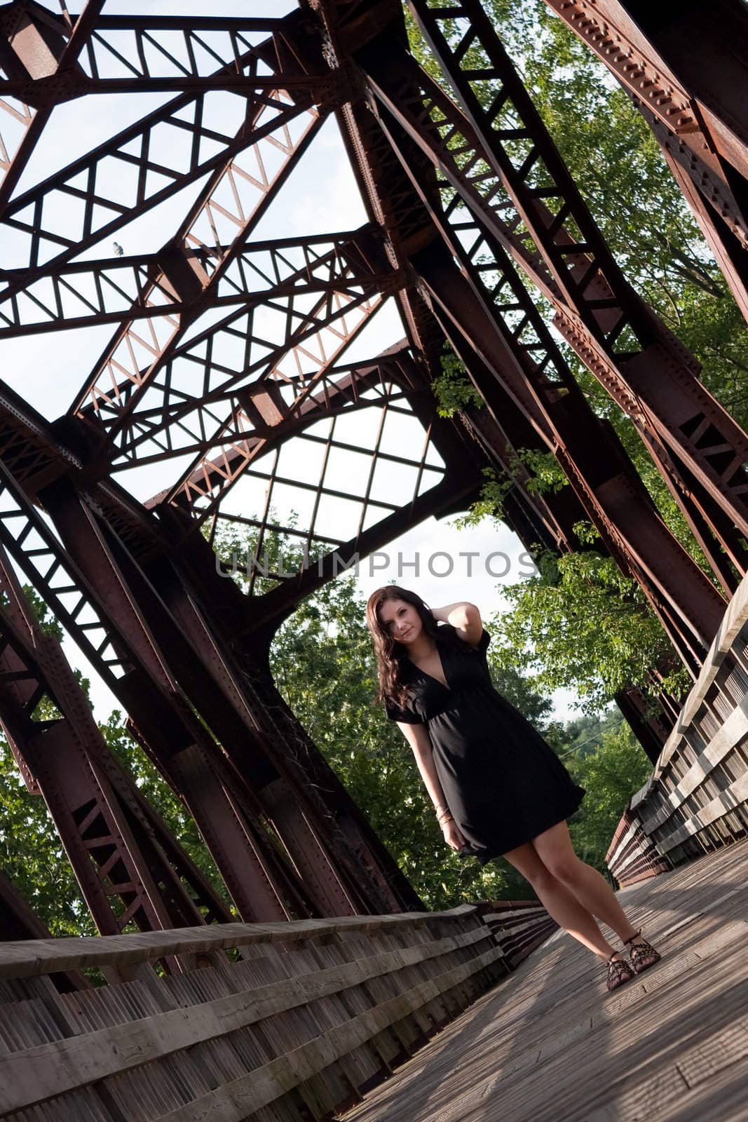 A carefree brunette woman walking along an old rusted bridge.