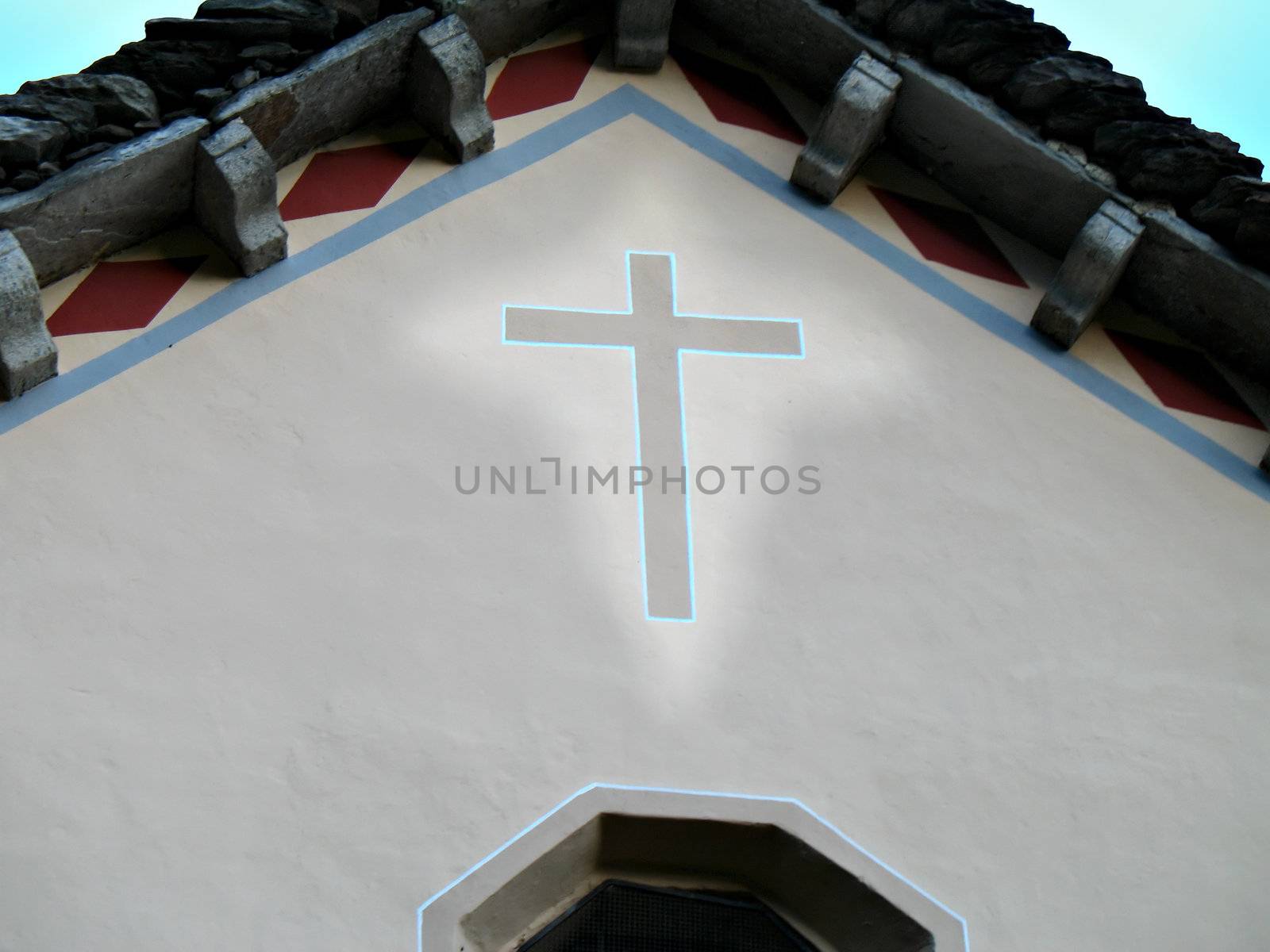 A small catholic church in the country with an illuminated painted cross