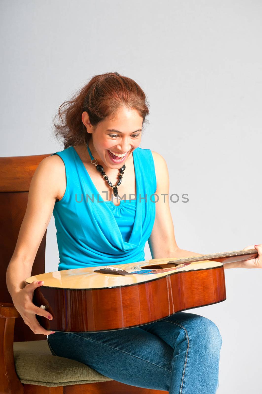 Pretty brunette girl surprised with a guitar as a gift. She shows her happiness and joy.