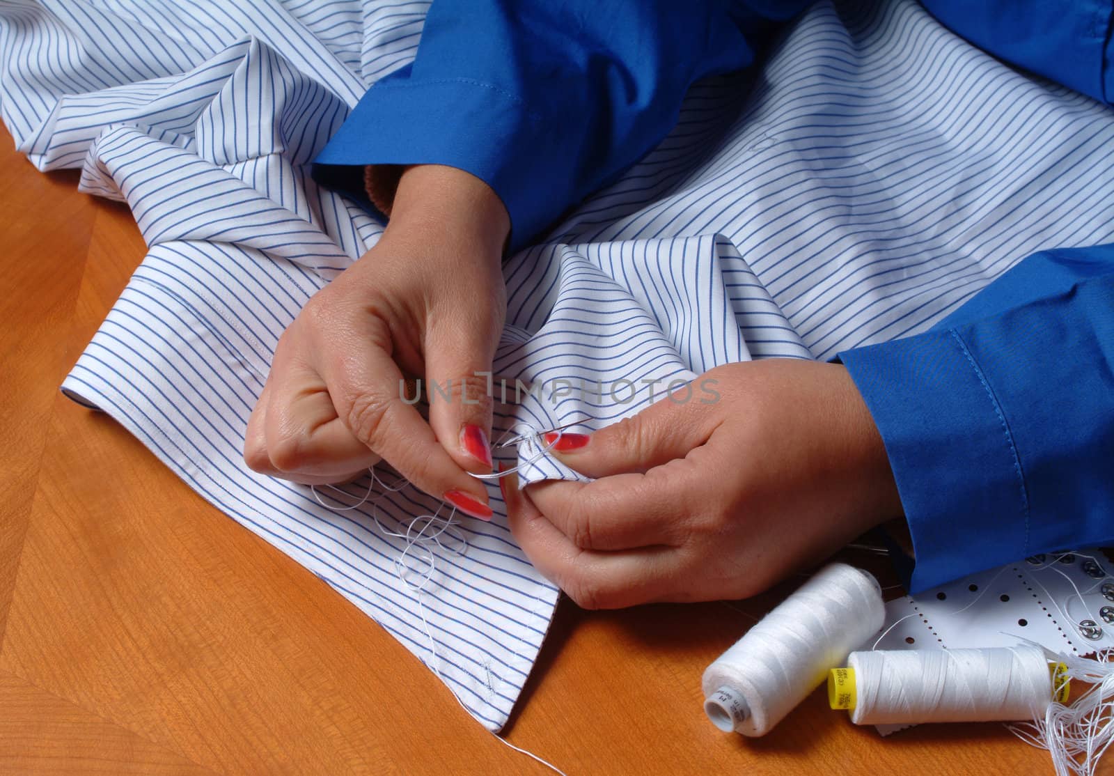 Close up of tailor's hands sewing on businessman clothes