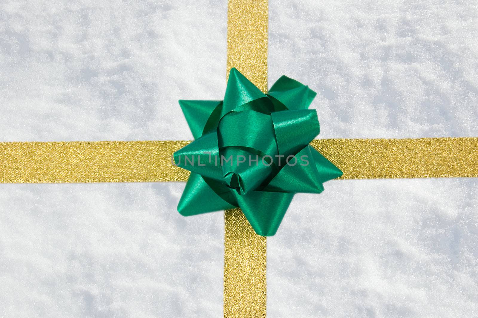 a golden ribbon and a green bow on a snow crystals background