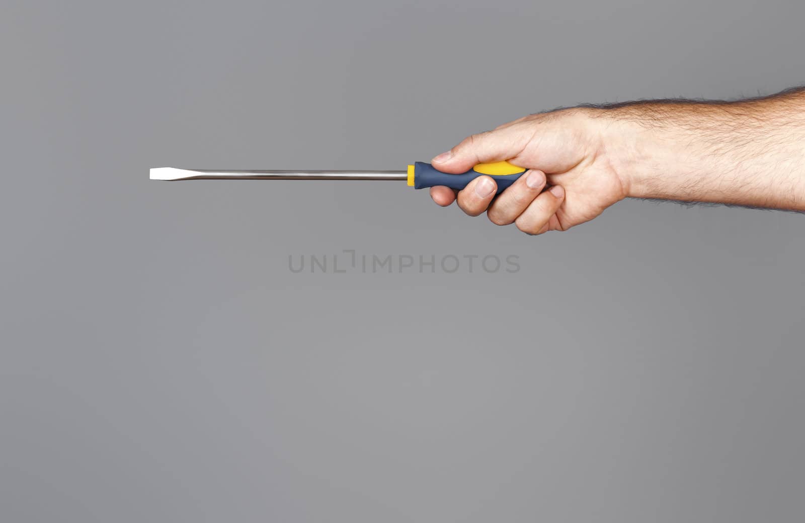 An image of a screwdriver with hand over grey background