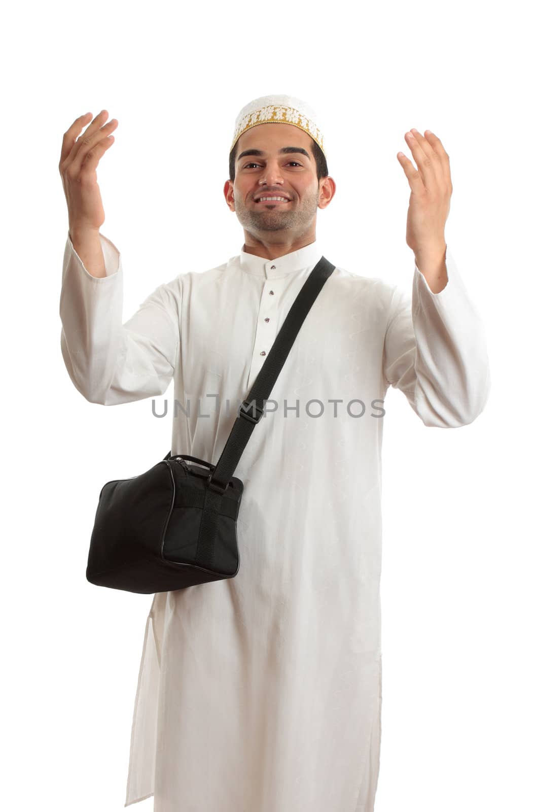 Ethnic mixed race man wearing white embroidered robe  and topi hat and carrying black shoulder bag and arms raised in praise or joy