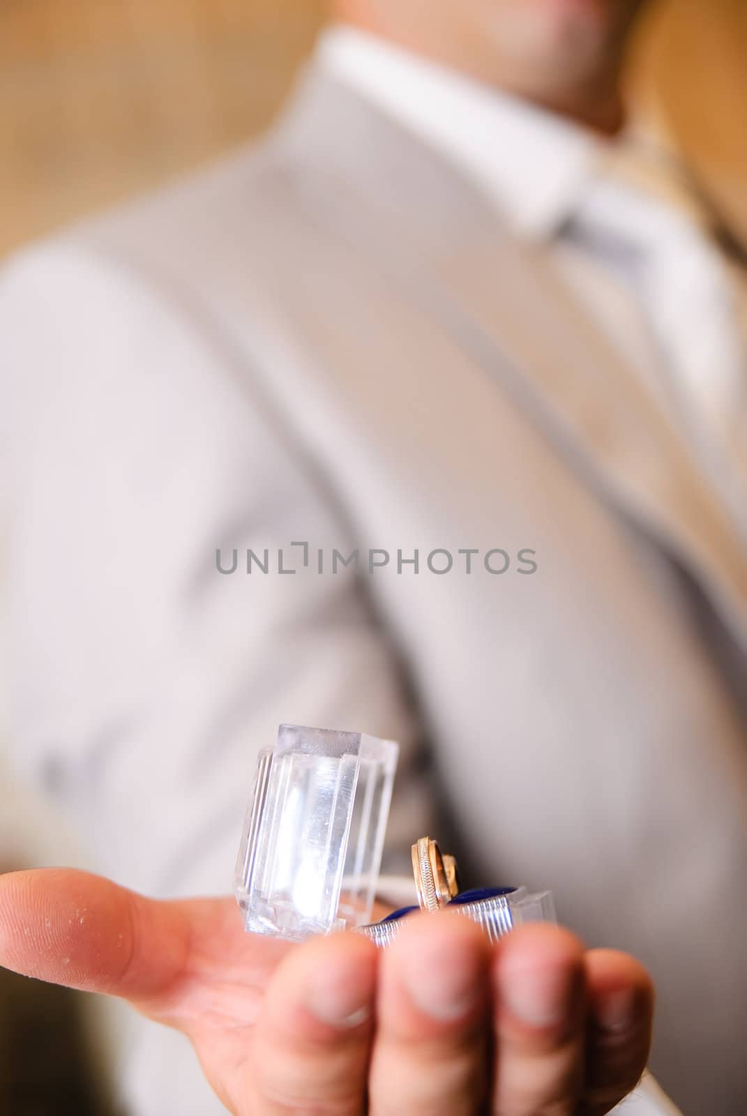 man's hand holding a transparent box with a wedding bands