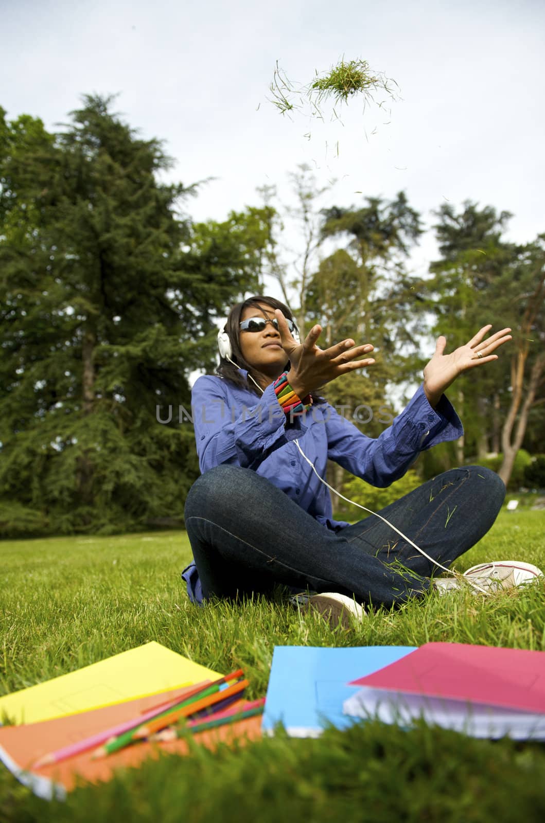 Black woman listening to the music in a park with white headphones