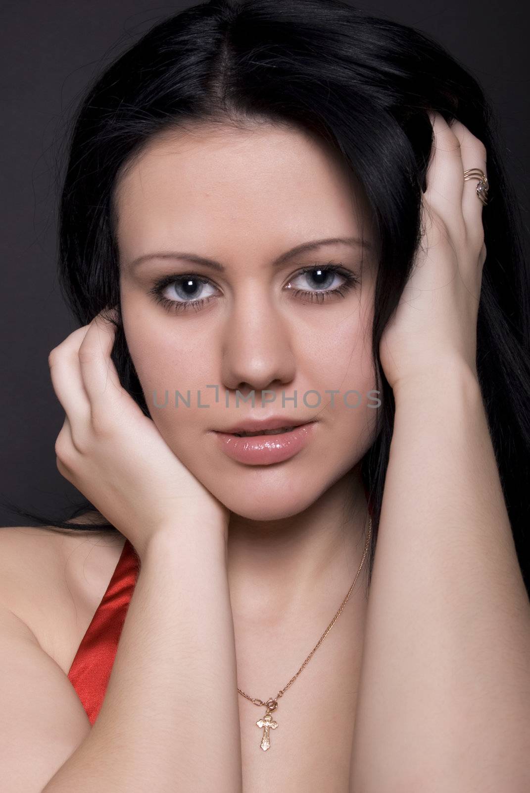 Portrait of a young beautiful seductive brunette with the hands on the face