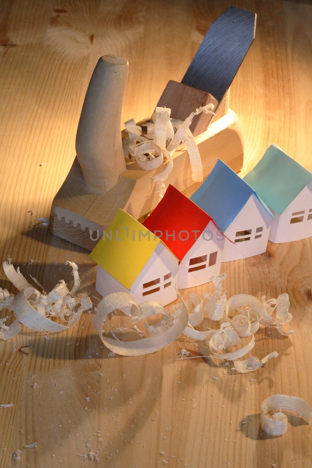 Few small paper houses near wood planer on wooden background