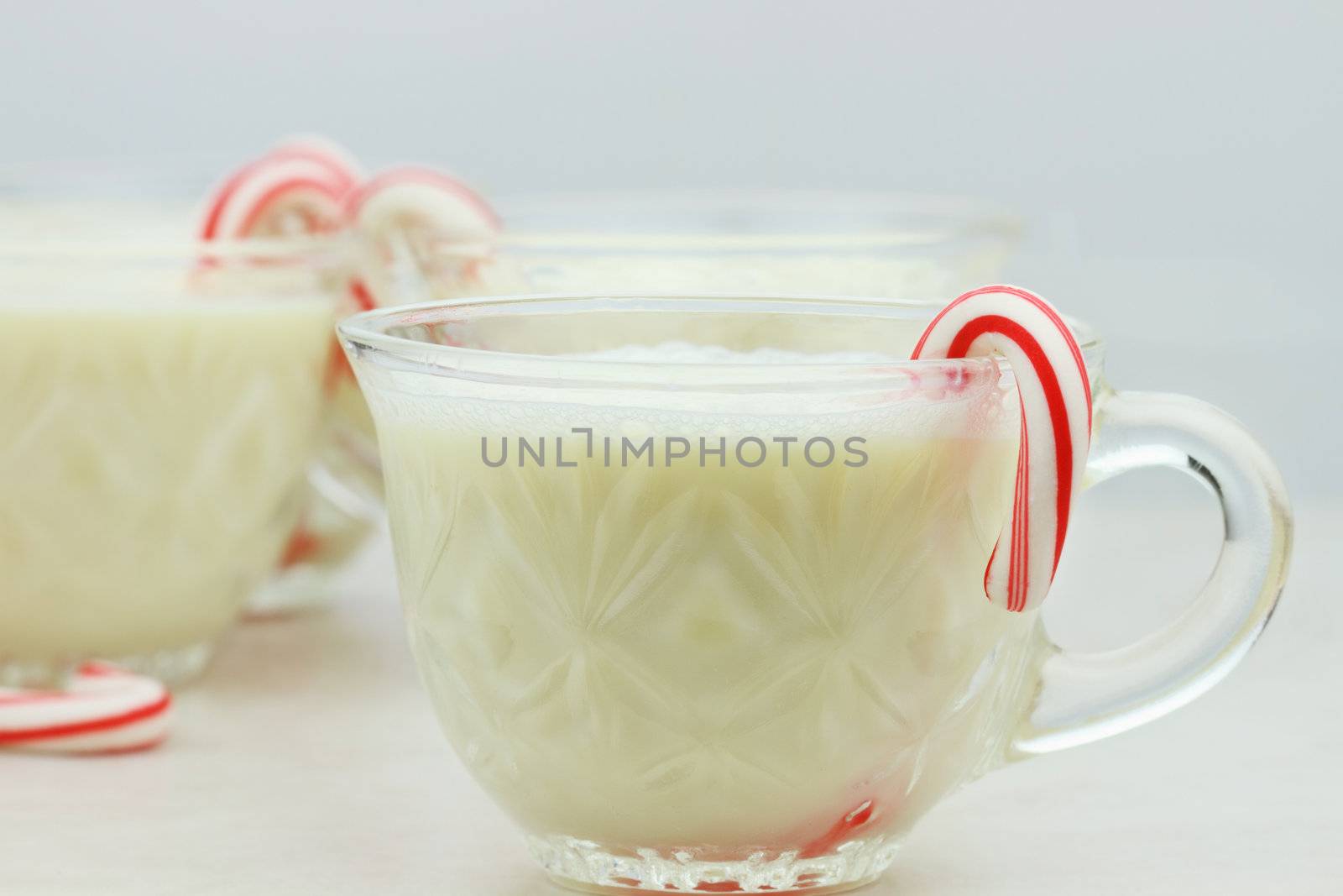 Delicious eggnog with mini candy canes. Shallow DOF with selective focus on cup in foreground.
