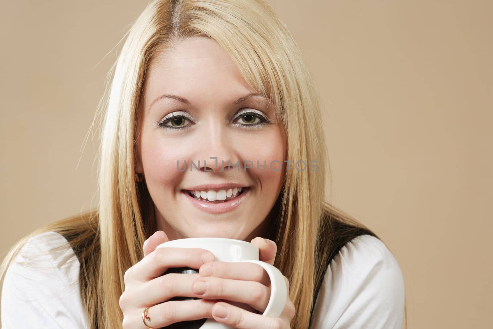 Photo of a smiling female holding a coffee, hot chocolate, or tea.
