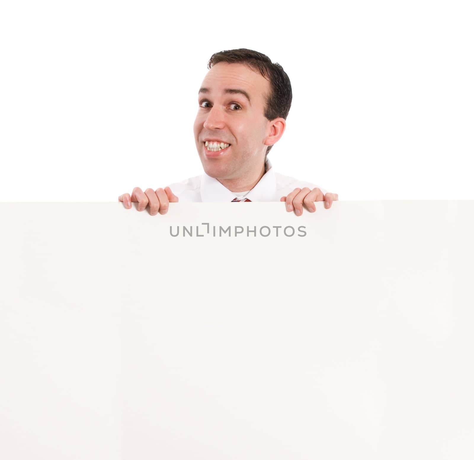 A young businessman smiling and looking over an office wall