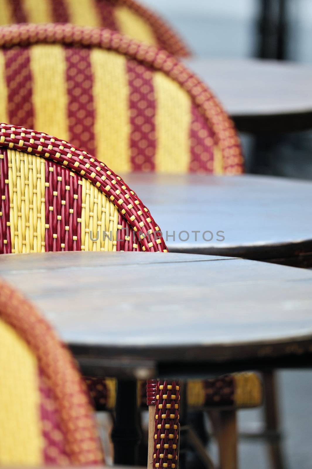 Round tables and wicker chairs in cafe in Paris. Photo with tilt-shift effect