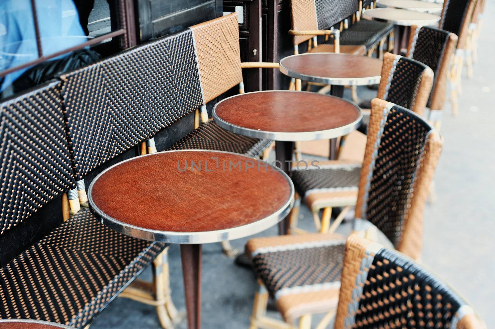 Round tables and wicker chairs in cafe in Paris. Photo with tilt-shift effect