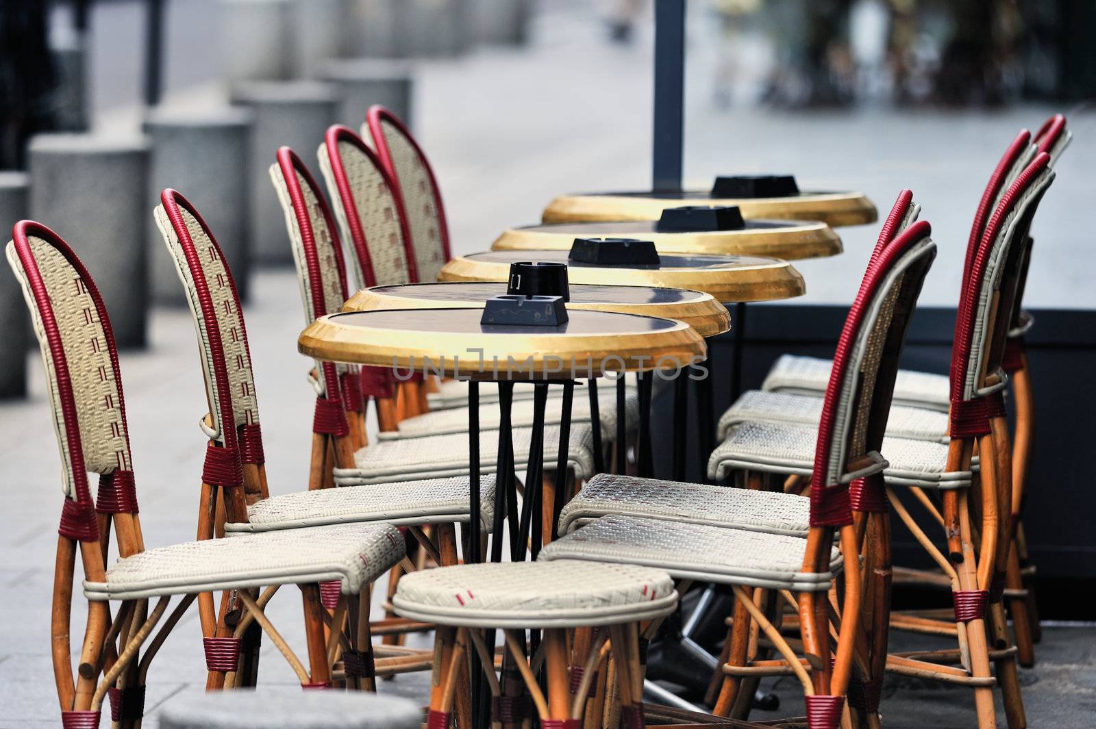 Round tables and wicker chairs in cafe in Paris. Photo with tilt-shift effect