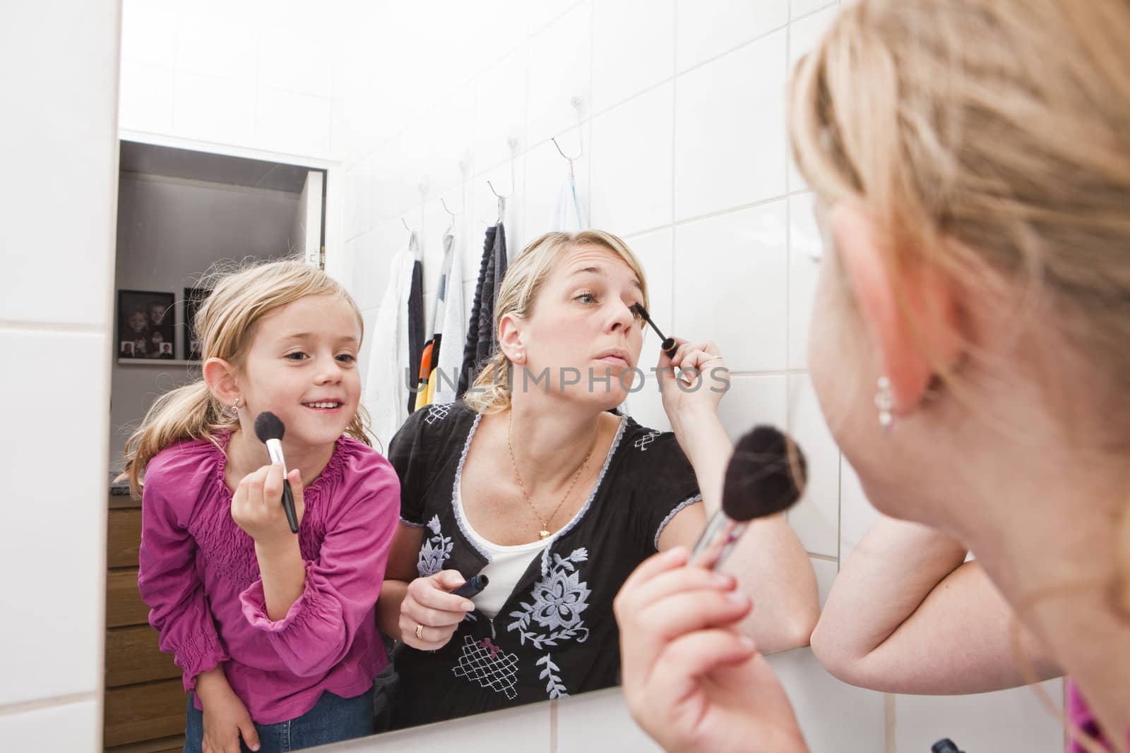 Mother and Daughter put on make-up in the bathroom