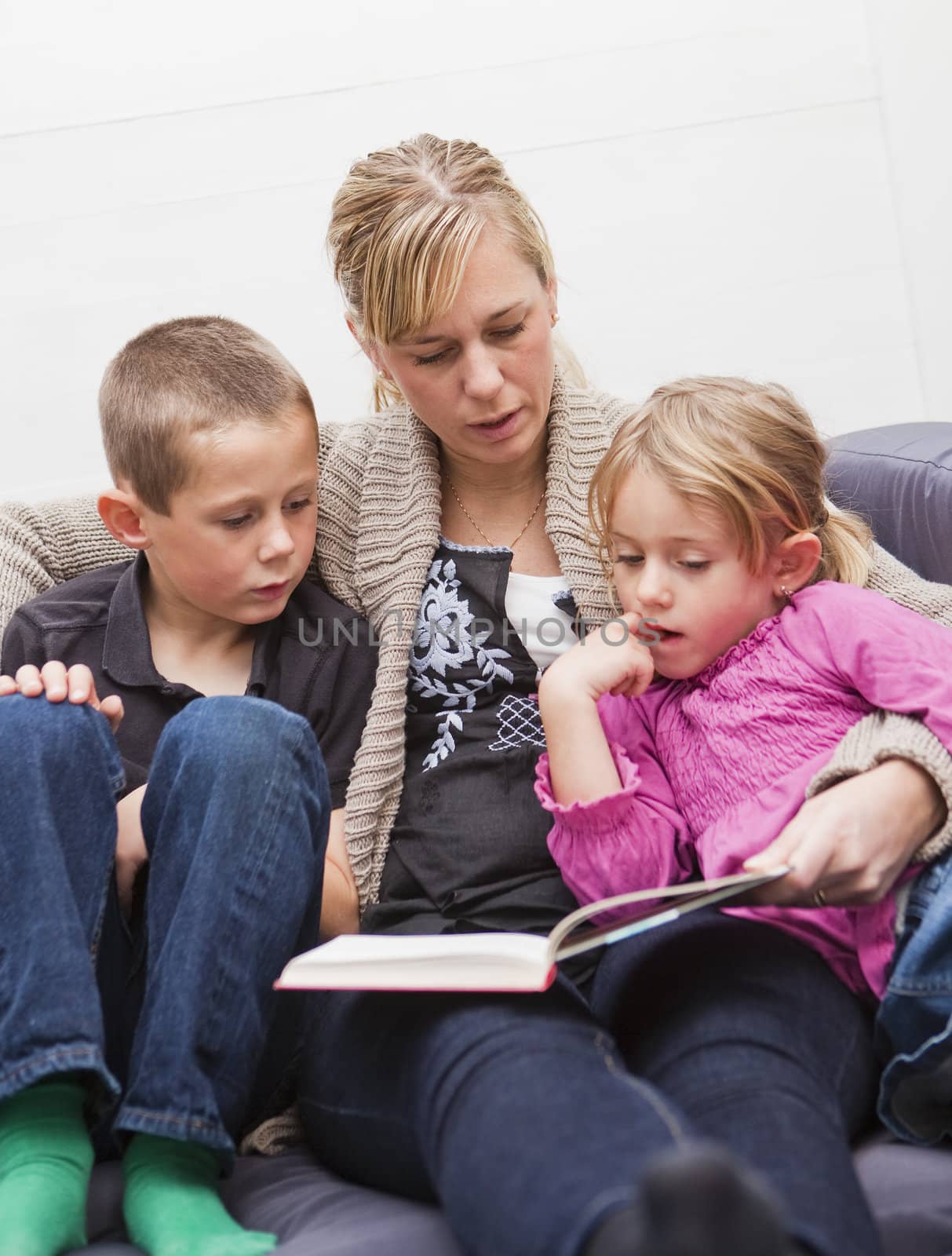 Mother in the sofa with her children reading a book