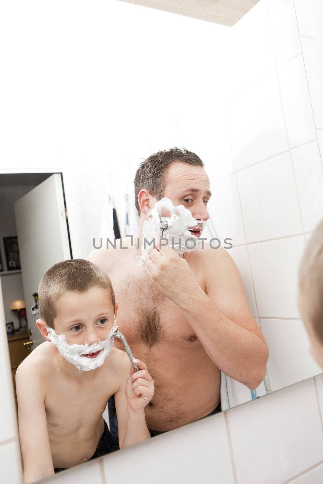 Happy Mature Man shaving in bathroom with his son