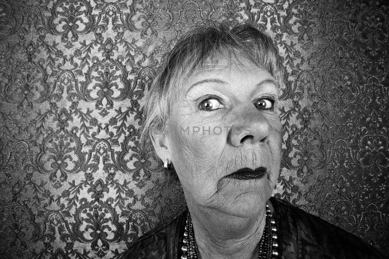 Portrait of snooty senior woman in front of gold background