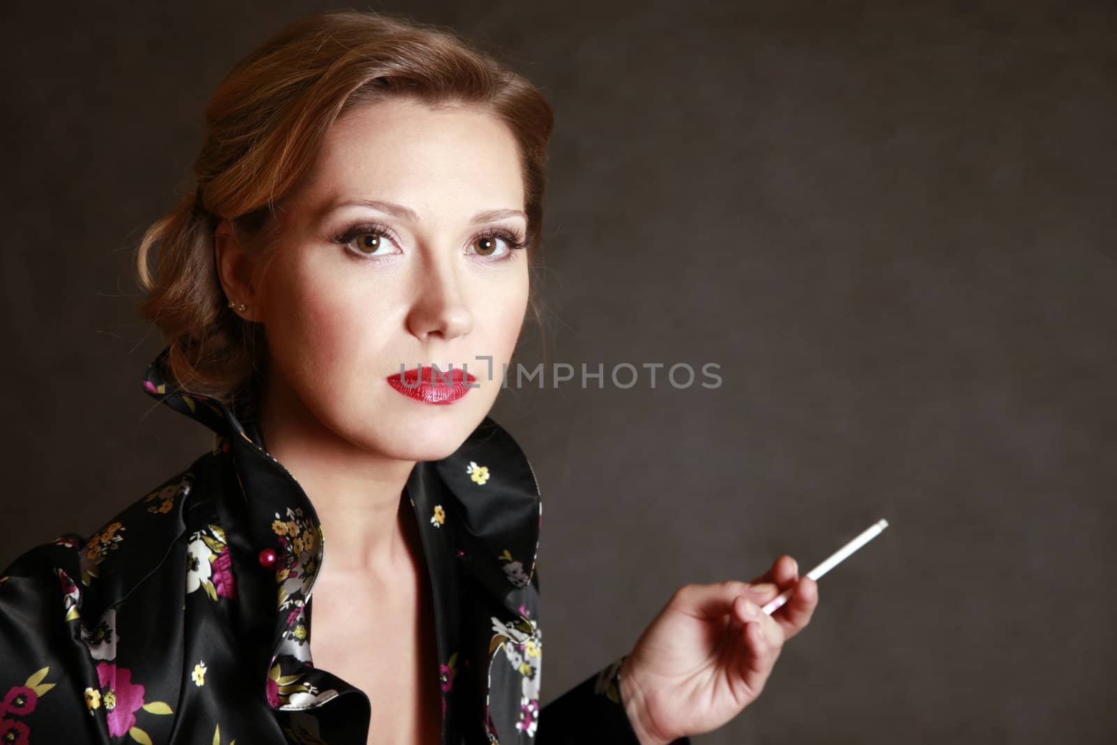 Portrait of the beautiful woman with a cigarette in studio