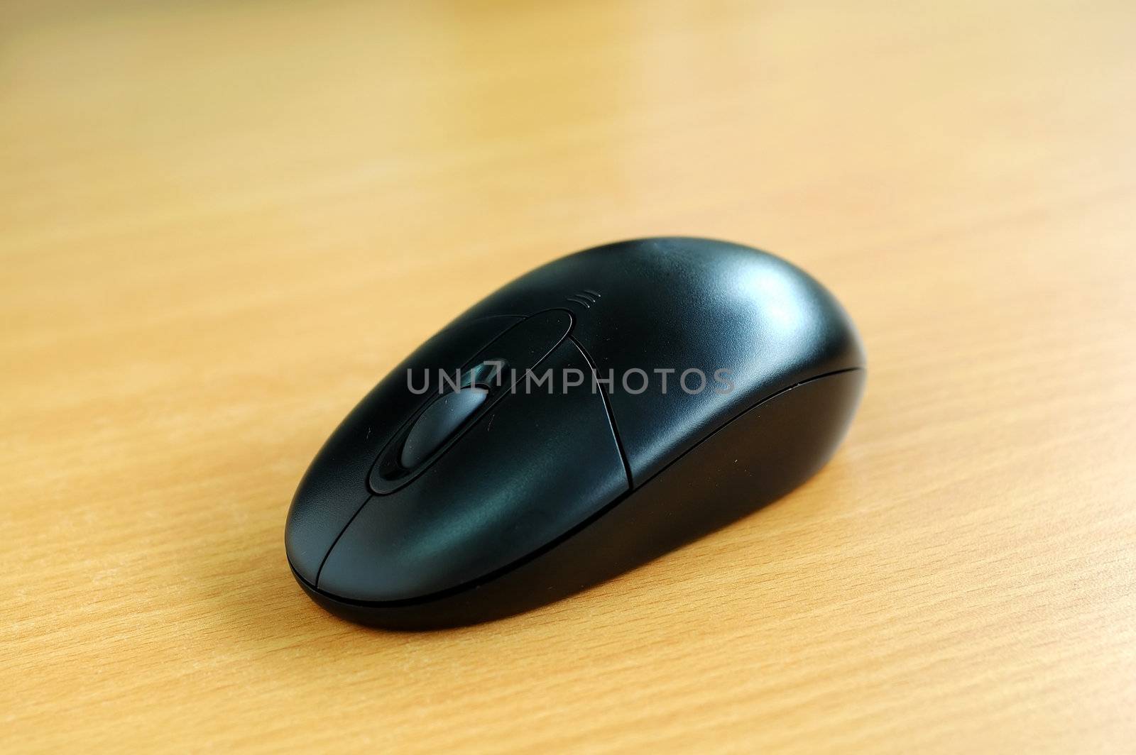 A black computer wireless mouse on a desk