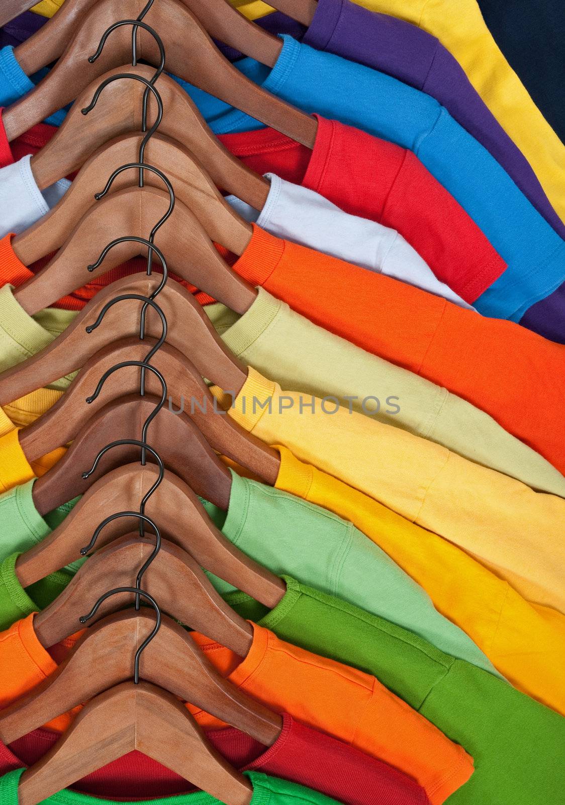 Choice of colorful casual clothes on wooden hangers.