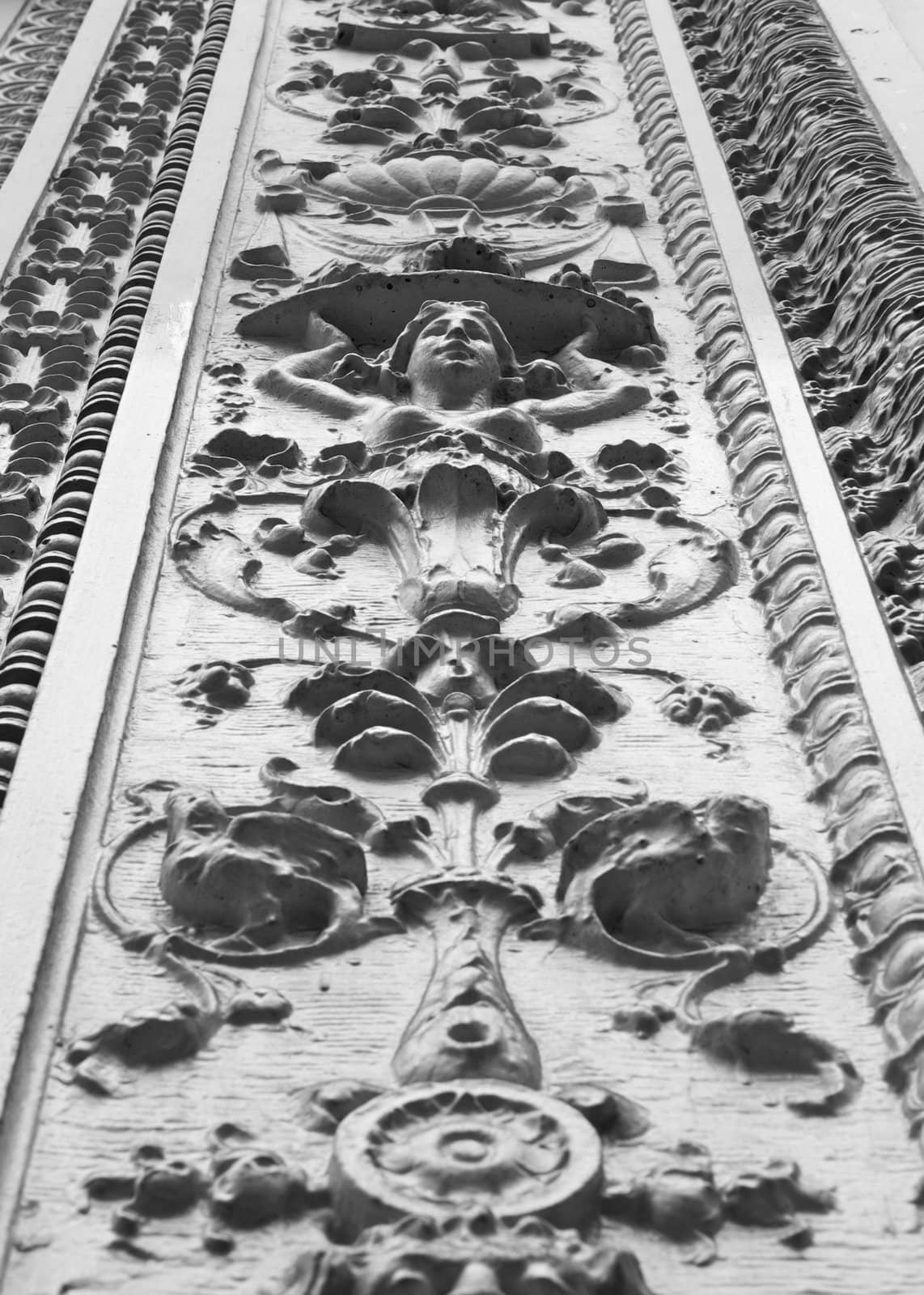 Black and white image of ornate design facade of building with female bust