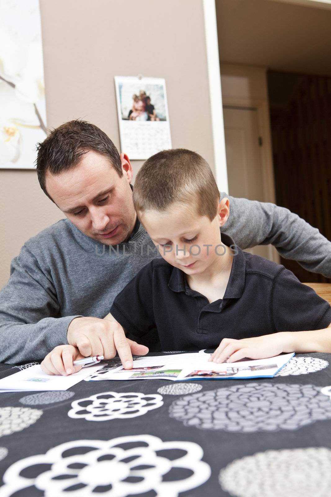 Father helping son with his homework sitting in at the table