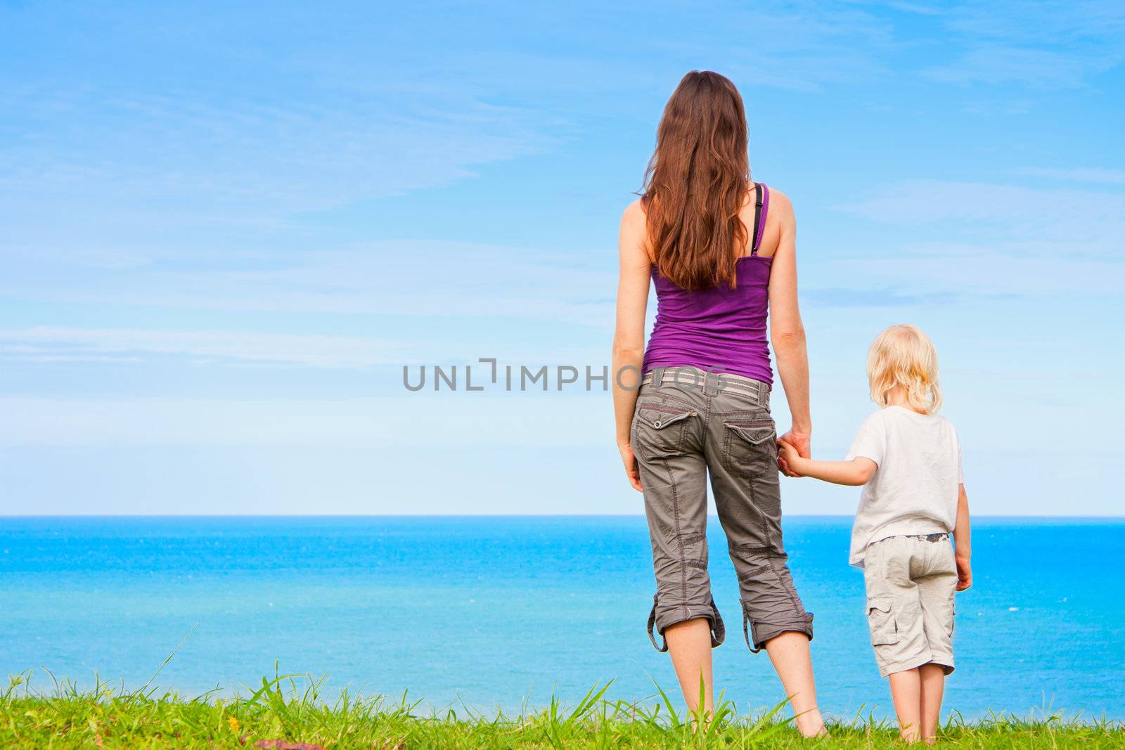 A young mother and child holding hands and looking at beautiful ocean view