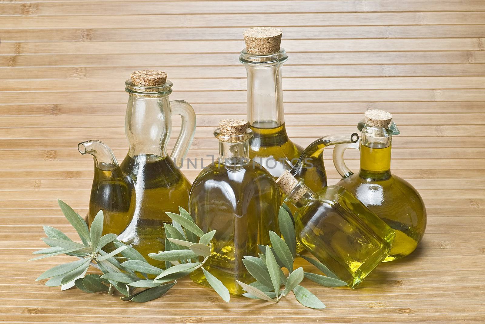 Olive oil bottles and olives on a bamboo mat.