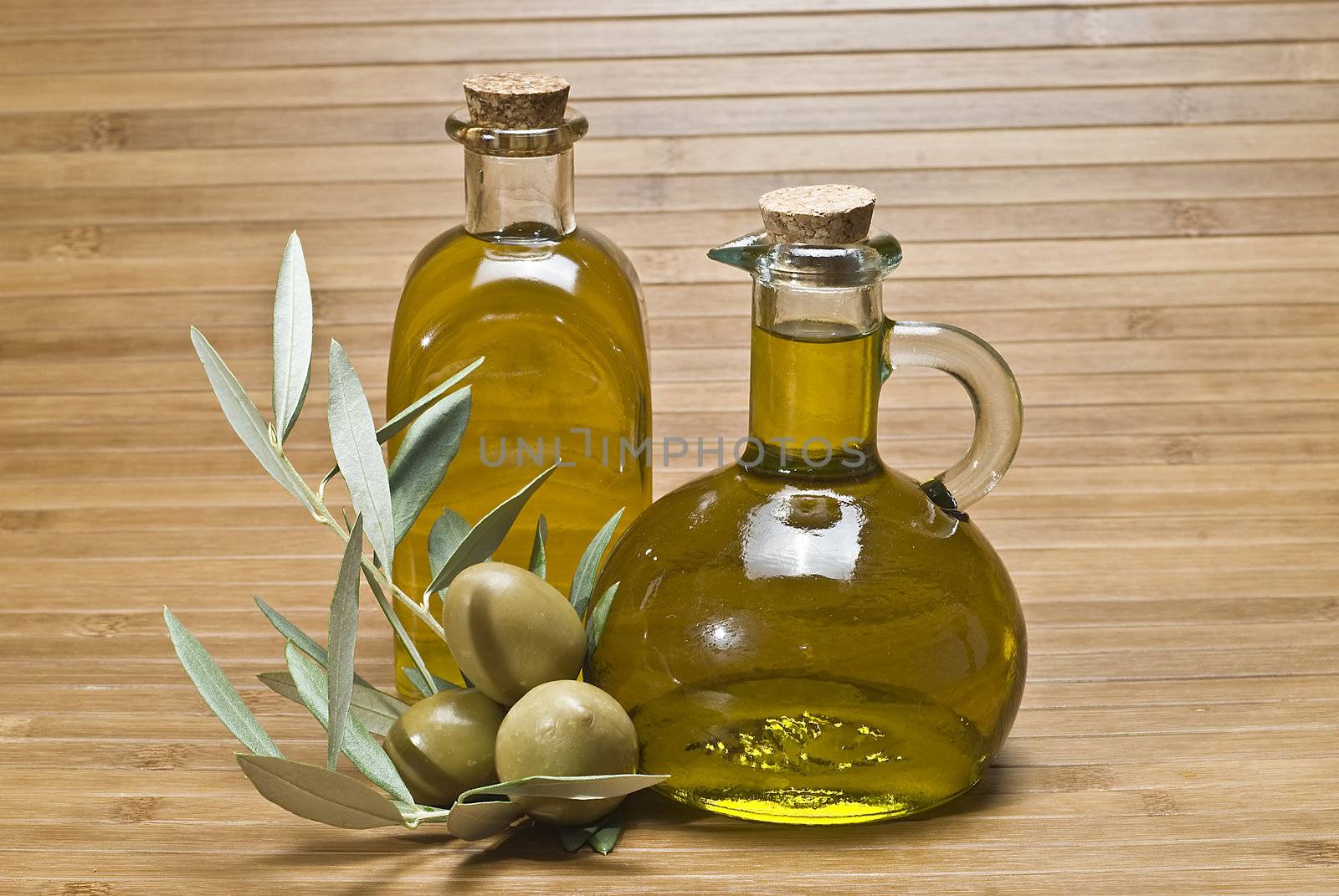 Olive oil bottles and olives on a bamboo mat.