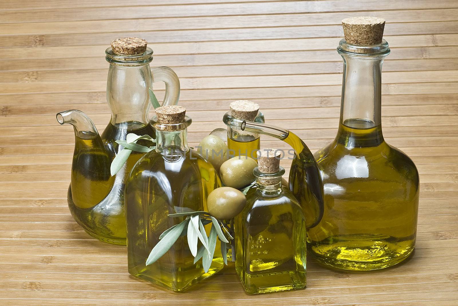 Olive oil bottles and olives on a bamboo mat.