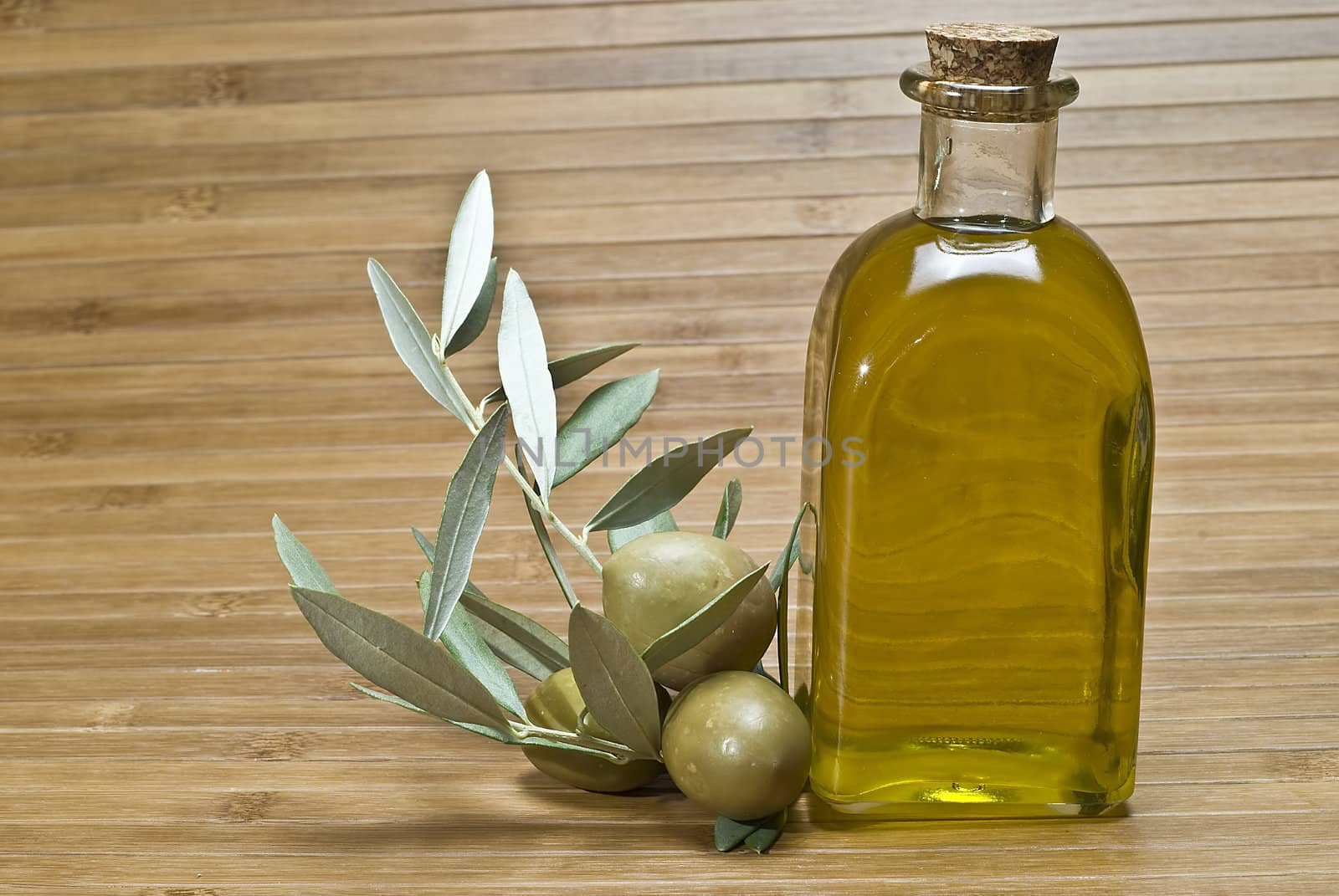 Olive oil bottles and olives on a bamboo mat.