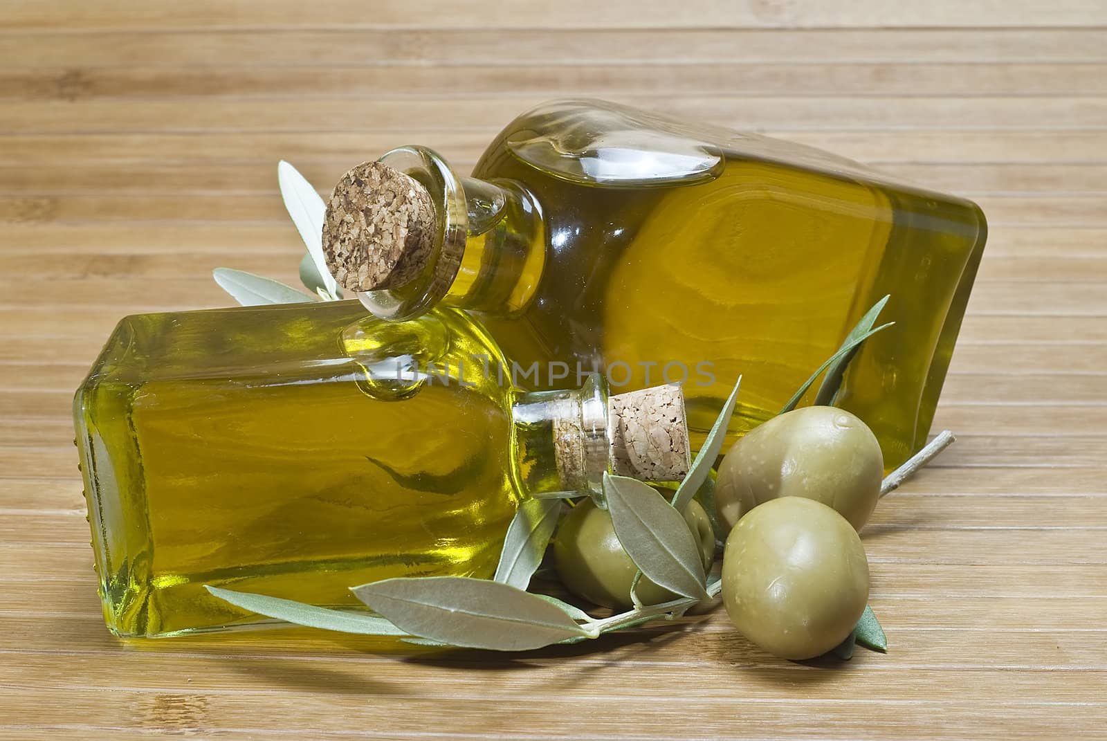 Olive oil bottles and olives on a bamboo mat.