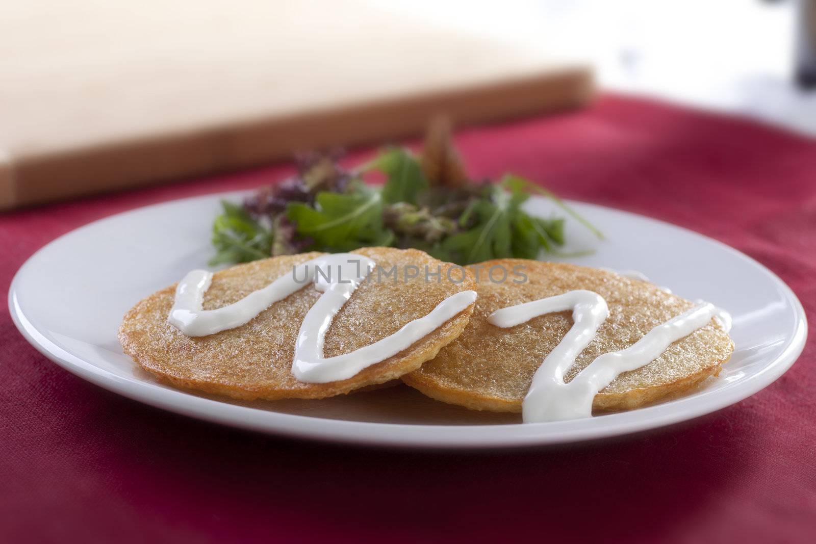 Potato pancake snack with sour cream and salad.