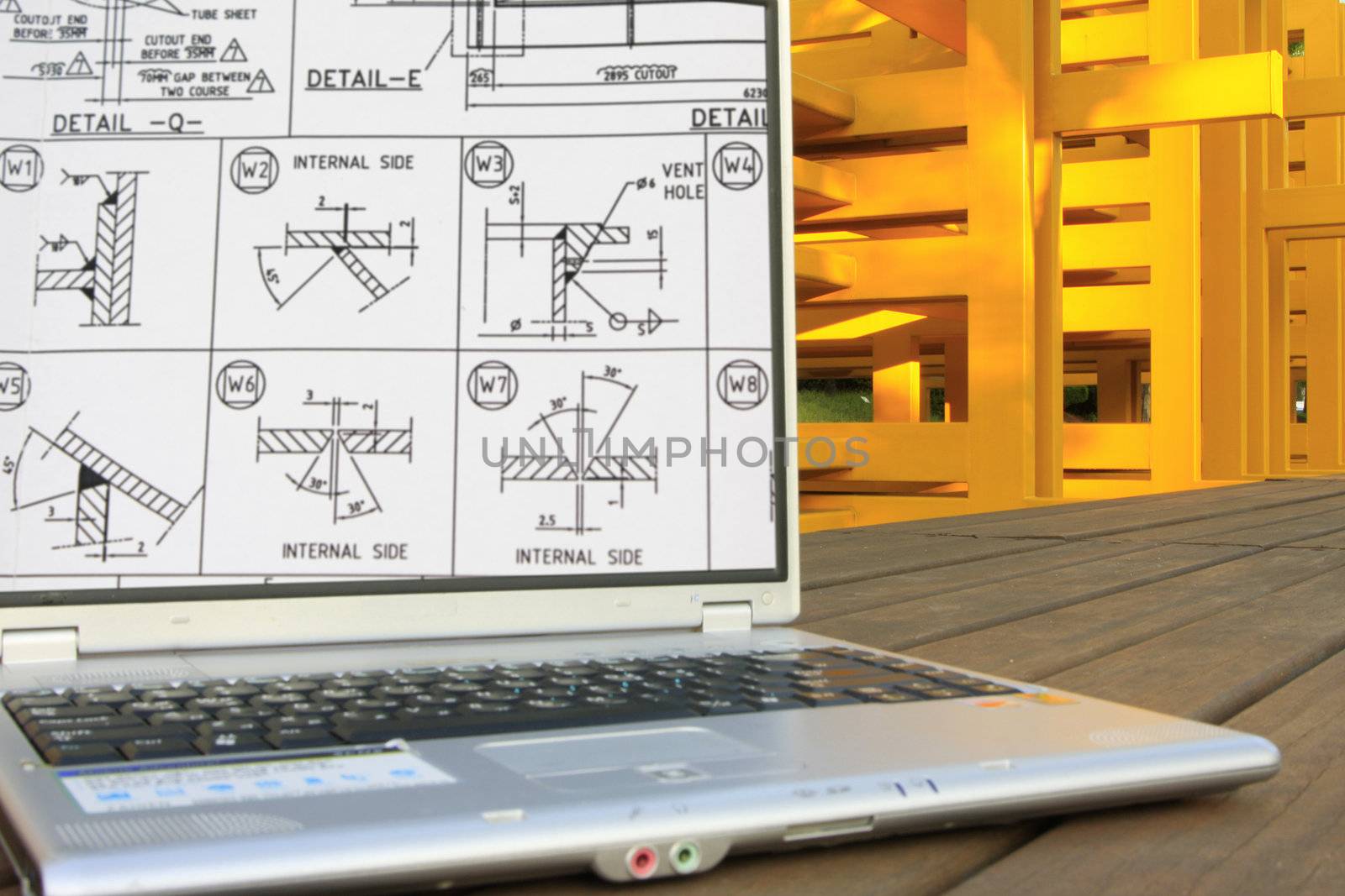 Welding works on computer with steel fabrication as background.