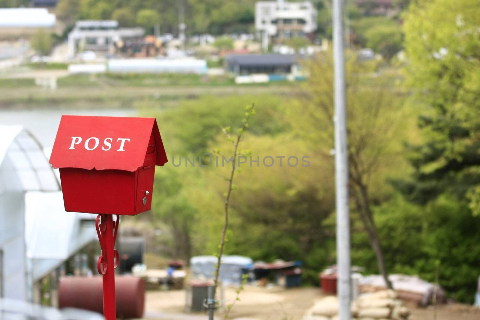 red post box  fixed to post in countryside.
