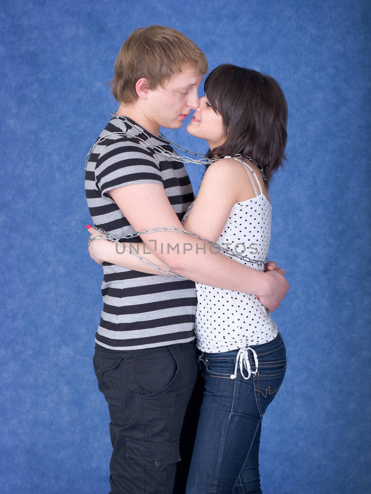 Loving couple chained by a chain on a blue background