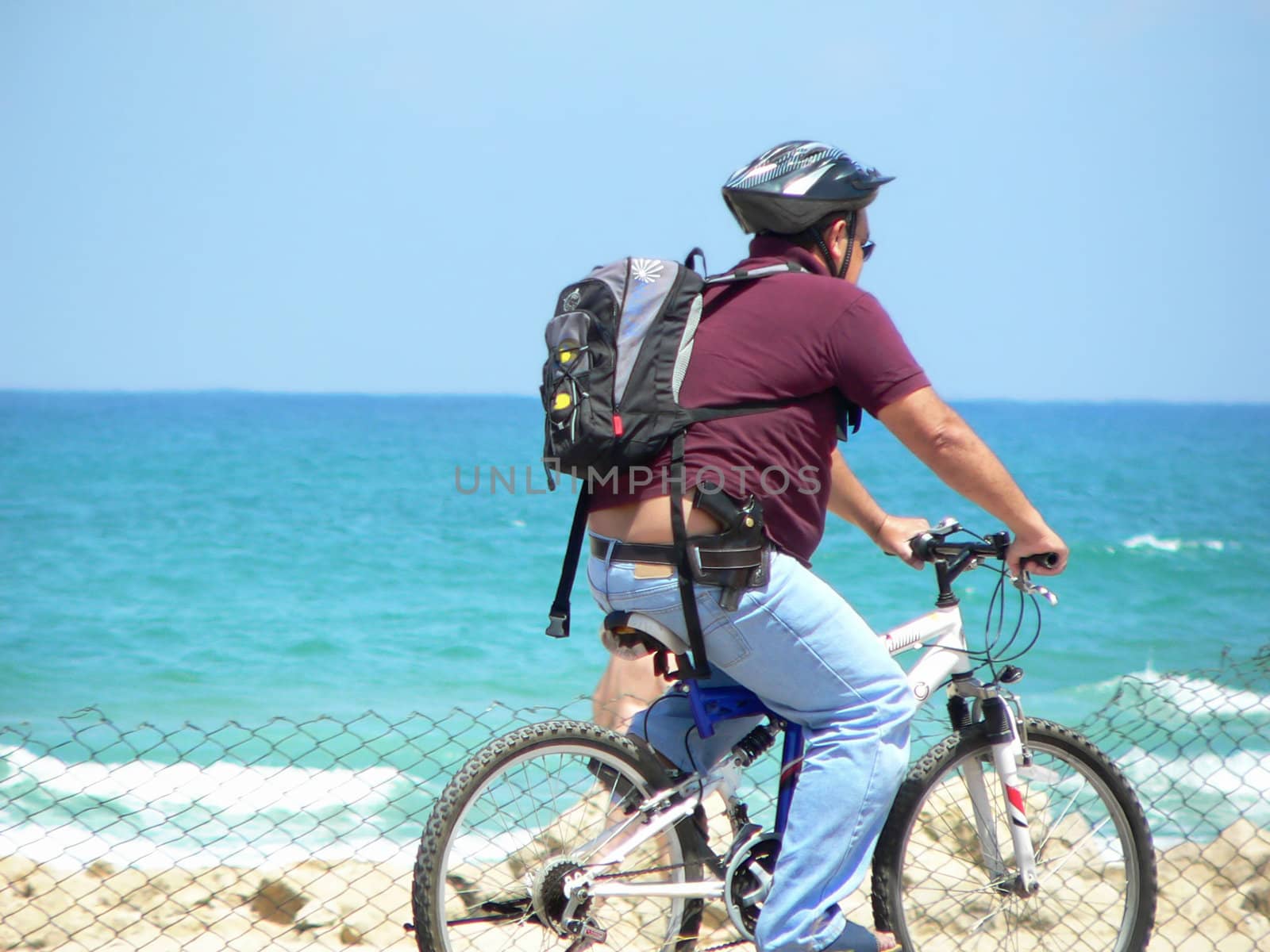 White middle age man with hard hat and gun on bicycle