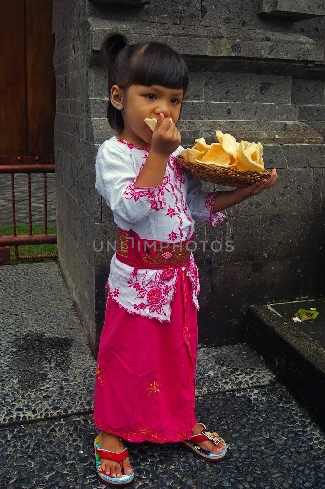 Bali (Indonesian) girl eating  Krupuk Udang(Prawn/Shrimp crackers), Jimbaran, Bali, Indonesia.