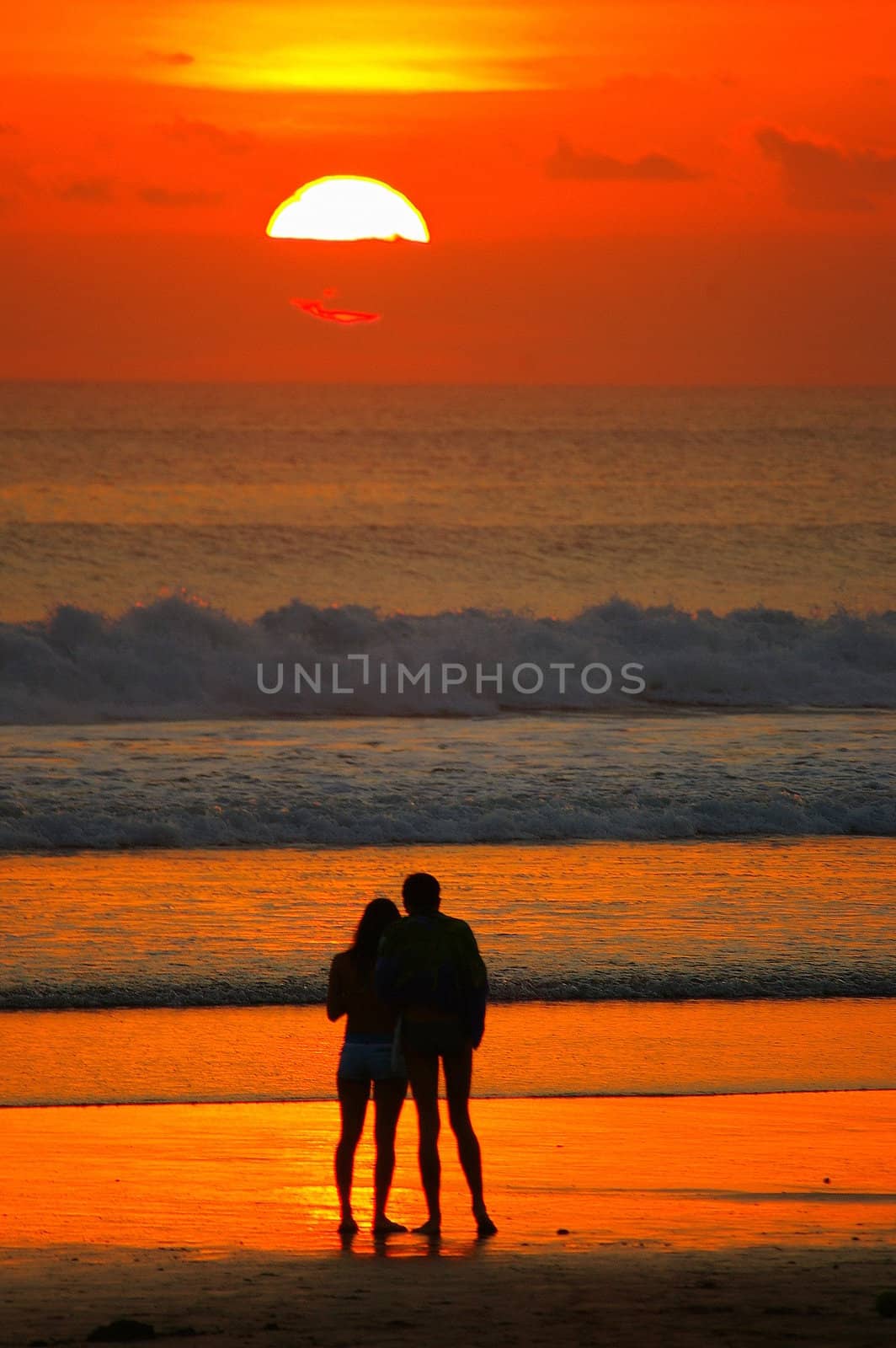 A couple admiring the sunset at Double Six beach, Bali, Indonesia.