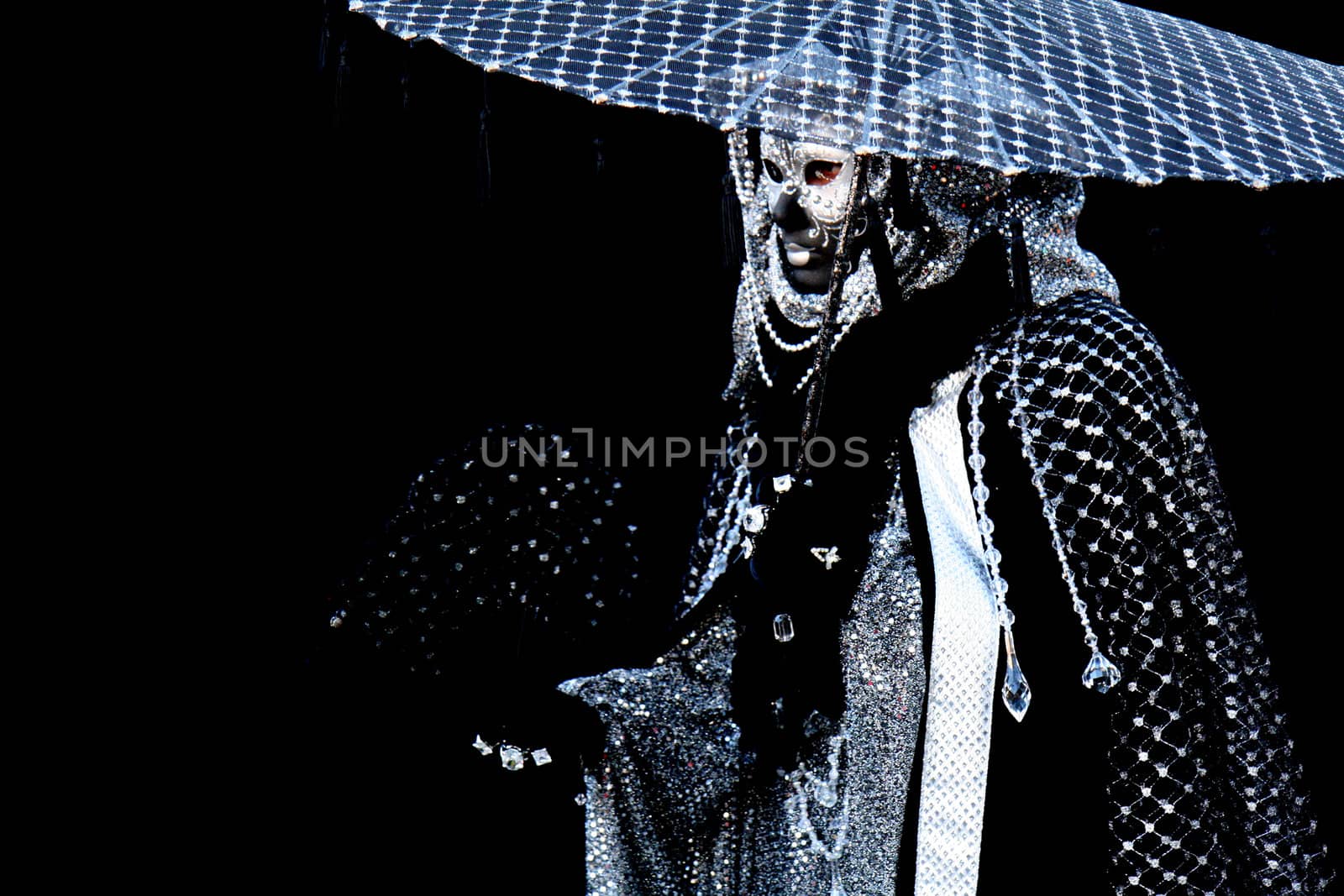 A masked man dressed in black, with a parasol, at the Venice Carnival