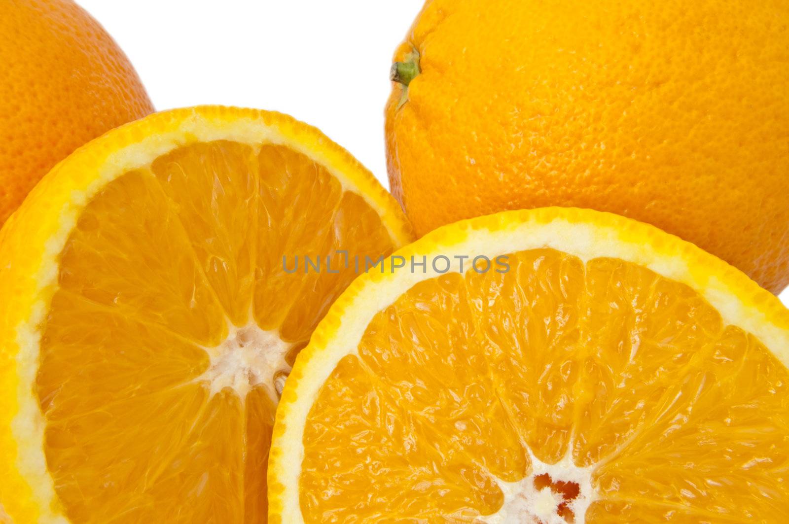 Close up of whole and cut oranges arranged over white.