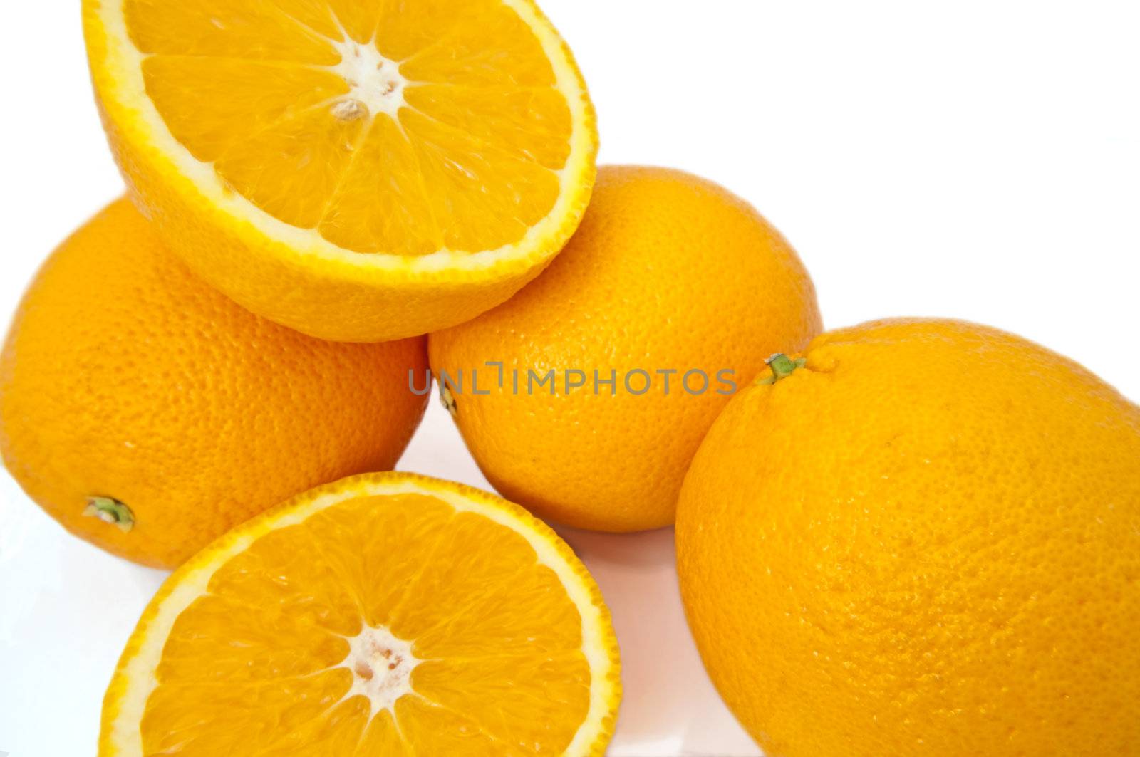 Close up capturing several fresh whole and cut oranges over white.