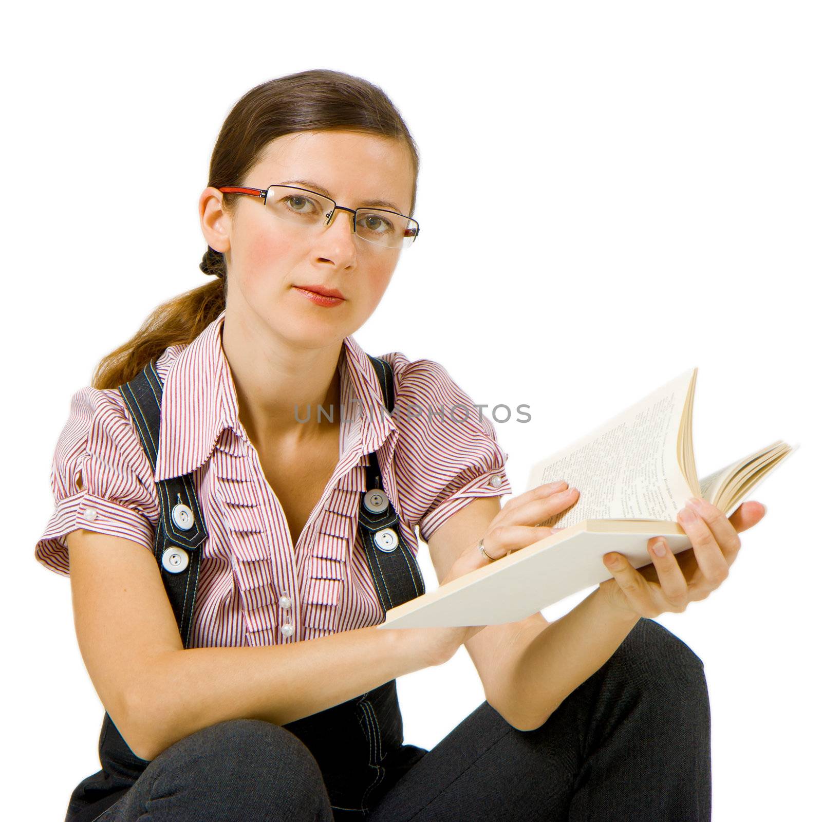 girl sits on an isolated background in glasses with a book

