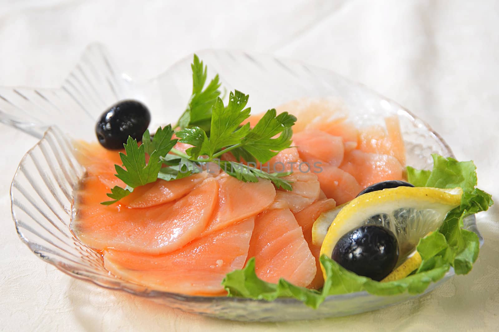 slices are filets of red fish, decorated a lemon, greenery and black olives