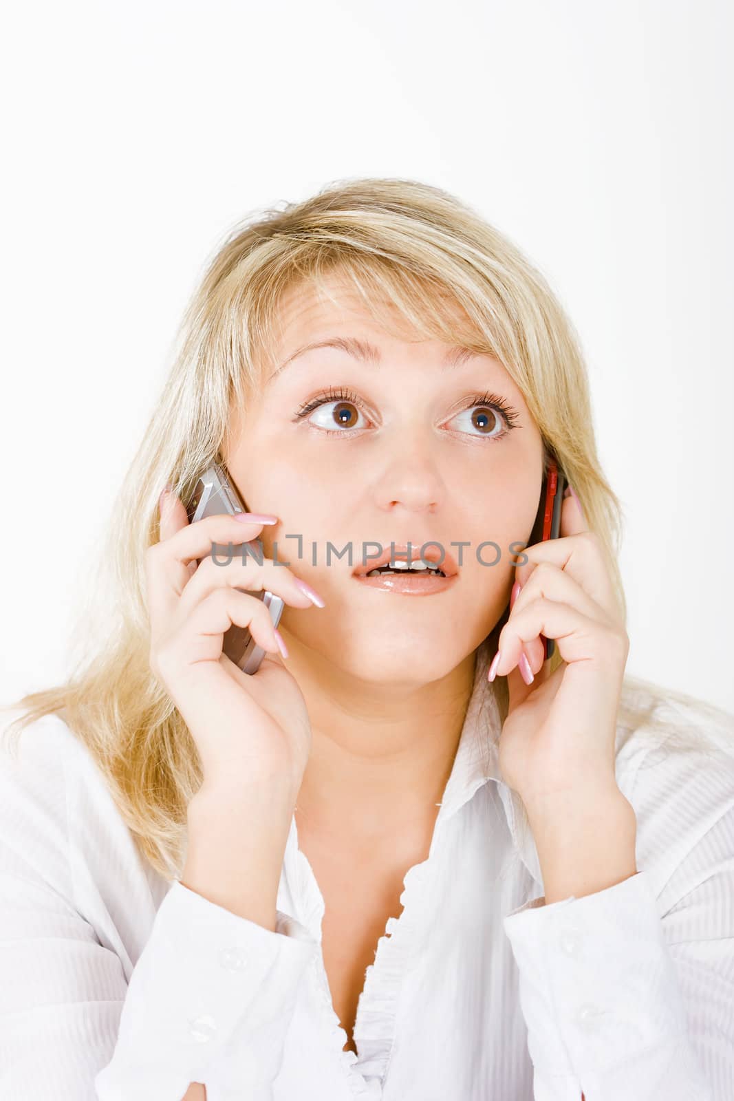 surprised blonde with two mobile phones on a white background

