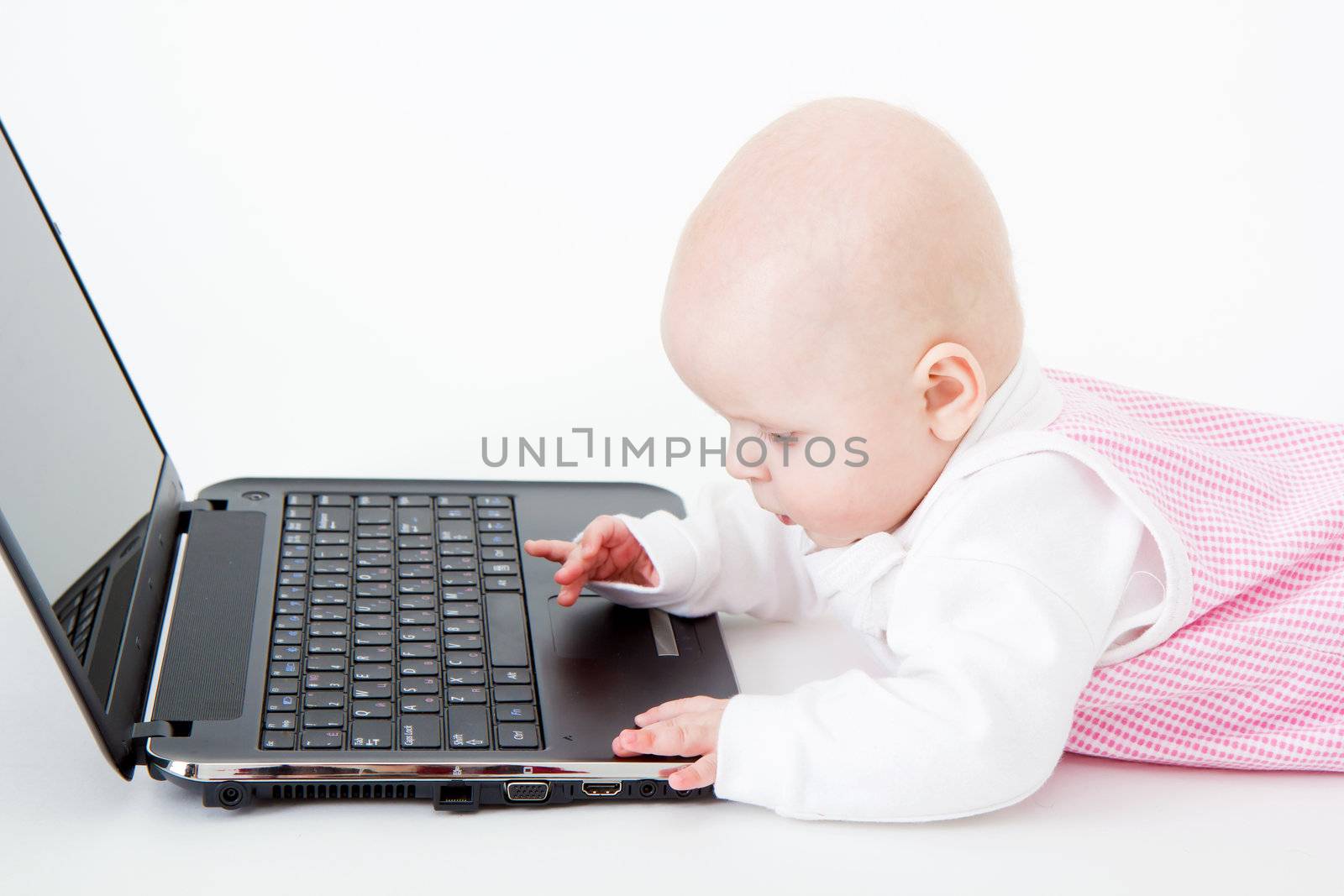 dressed the baby played with a laptop on a white background
