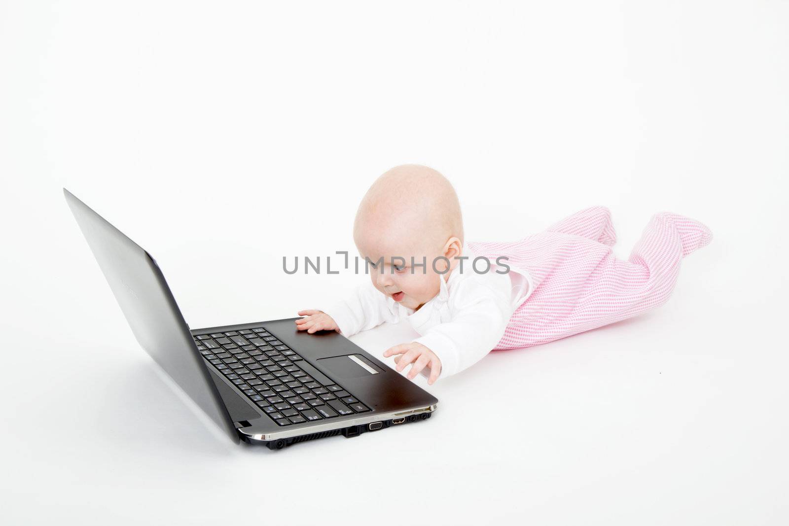 Baby playing with laptop on white background
