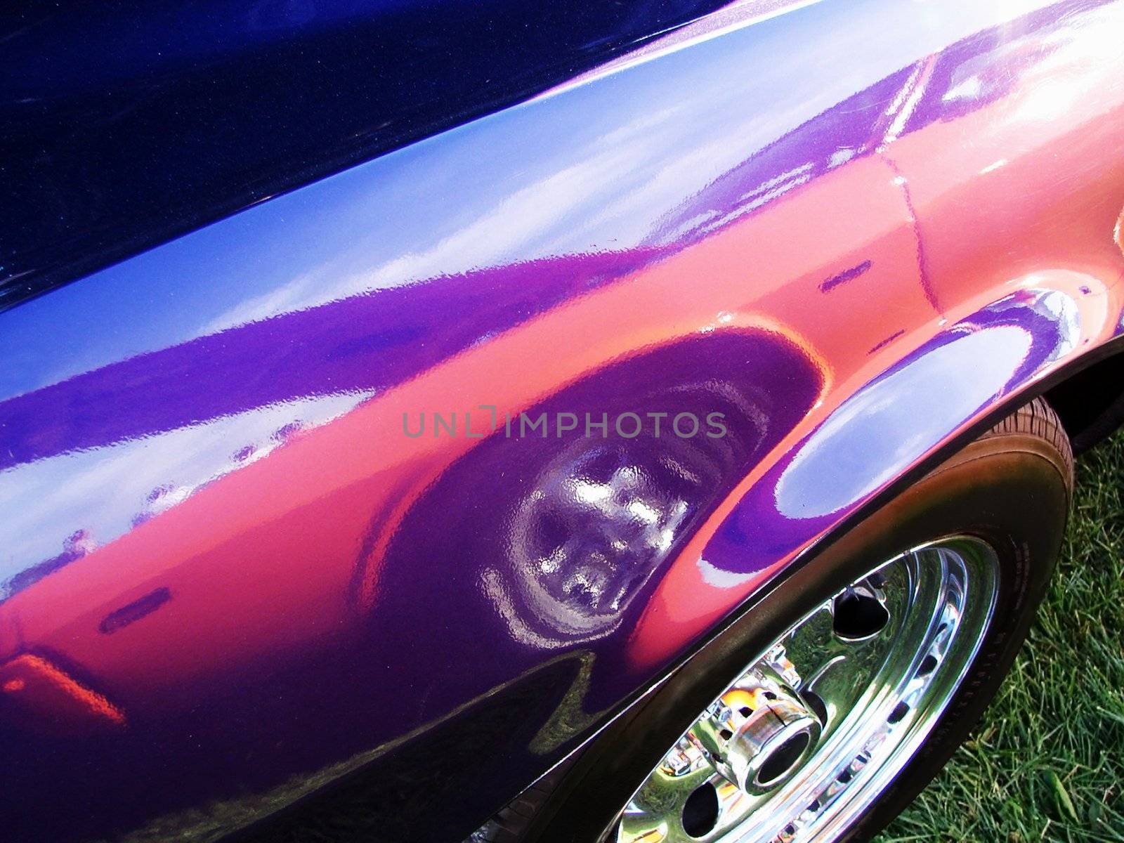 Reflection of an orange Hot rod onto the side pannel of a purple muscle car at a meet show                               
