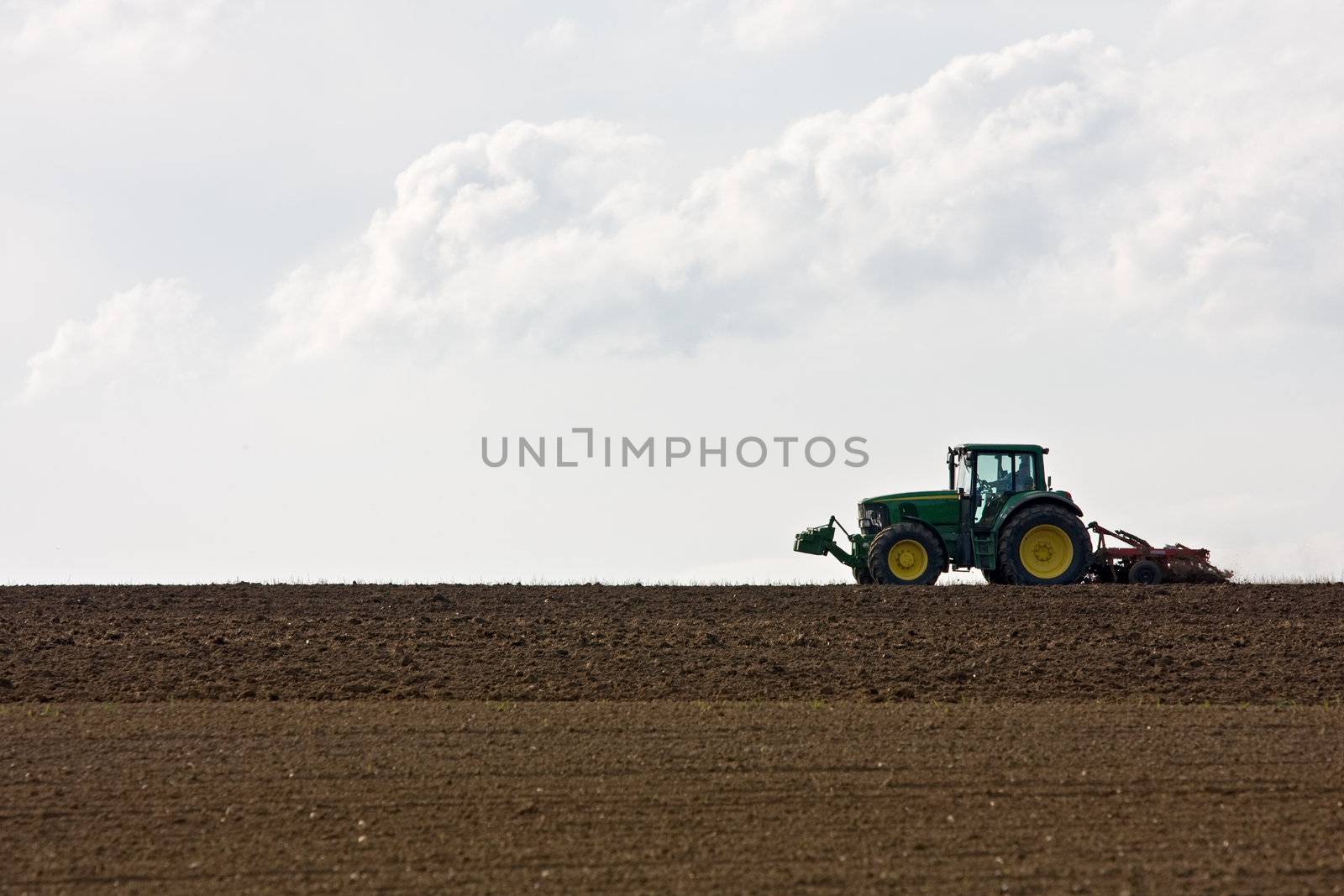 silhouette of a tractor on farmland by bernjuer