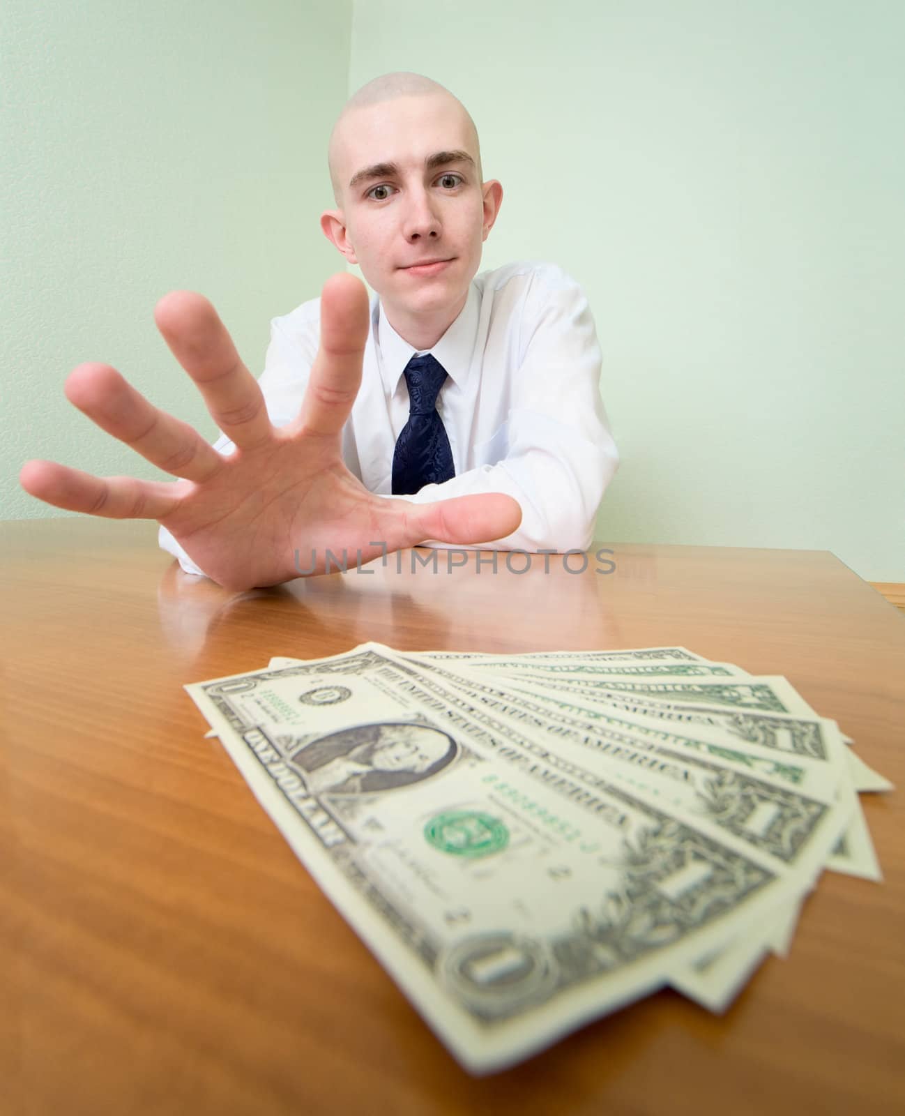 Young man reaches for a batch of money lying on a table